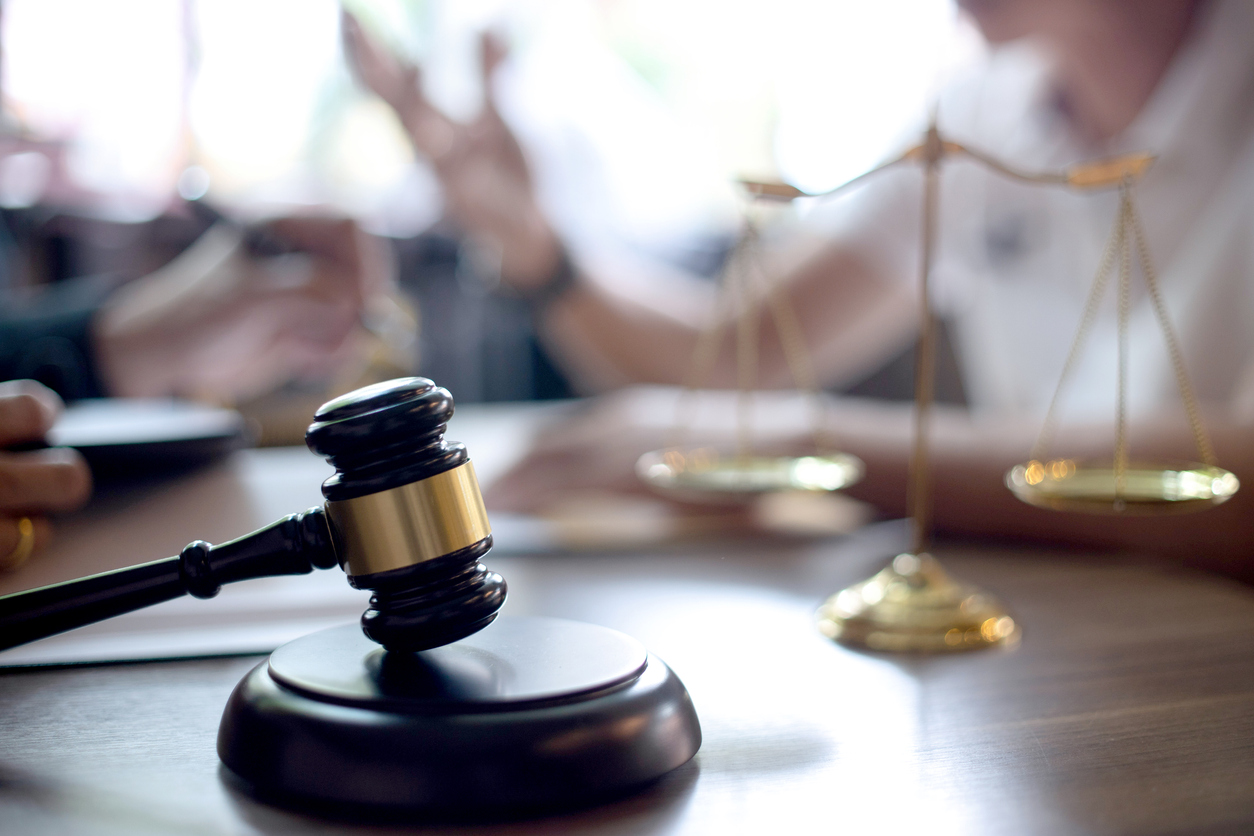 Probate attorneys sitting around a wooden desk discussing laws with a gavel in the foreground