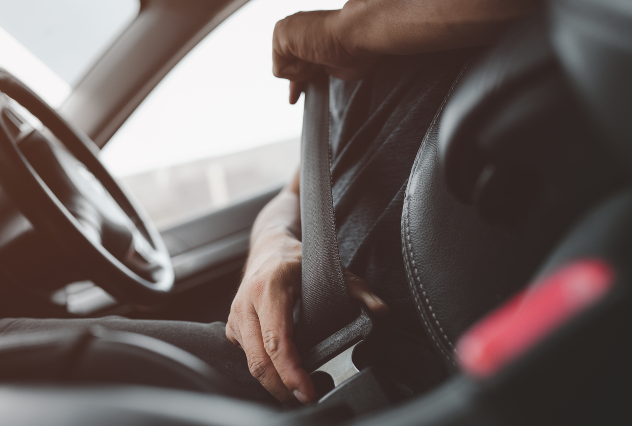 a man buckling in his seatbelt while sitting inside his car