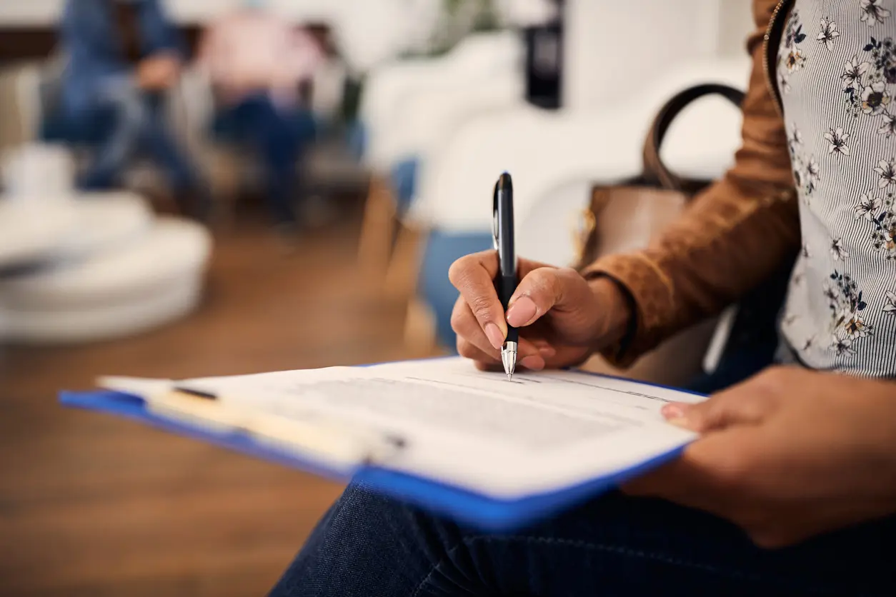 woman with pre-existing conditions filling out a clip board at a doctors office