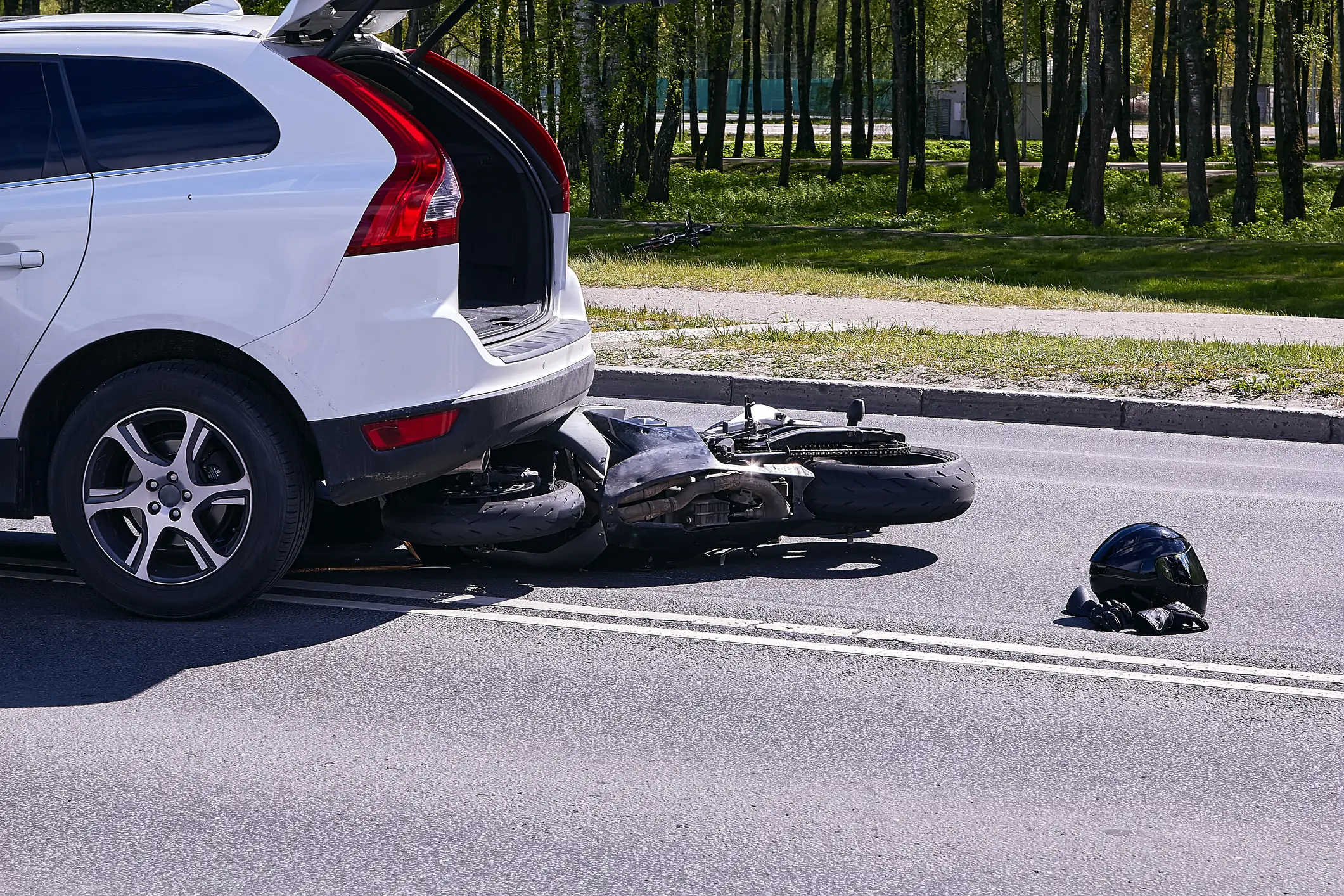 car that hit a motorcycle which is laying out in the middle of the road