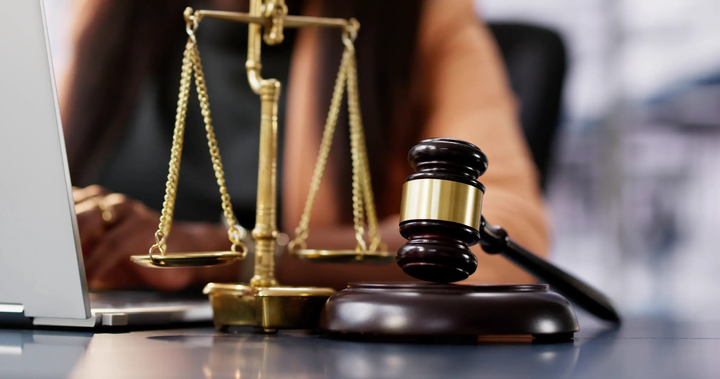 a personal injury lawyer typing on the computer with the scales of justice and a gavel in the foreground
