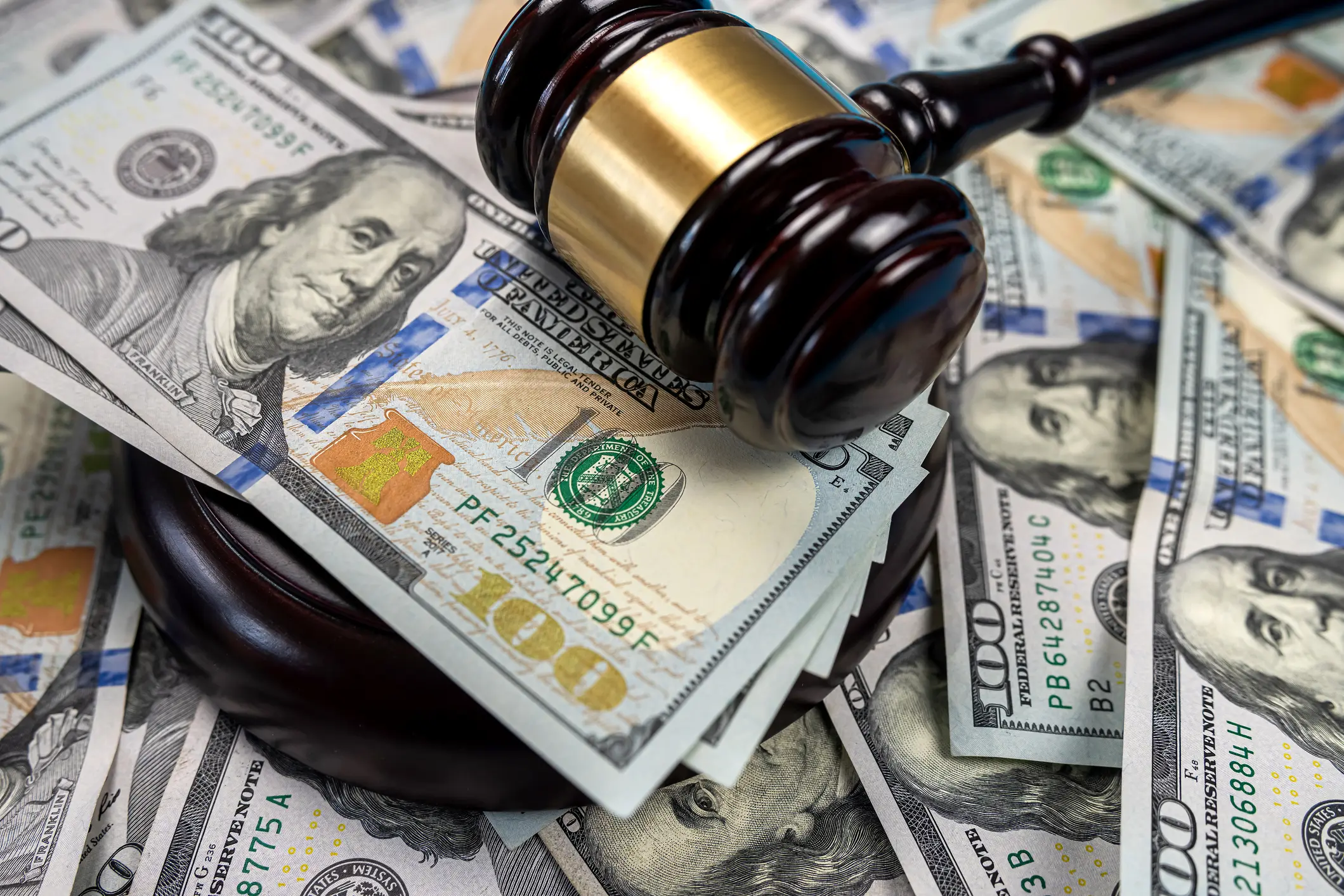 a gavel resting ontop of hundred dollar bills