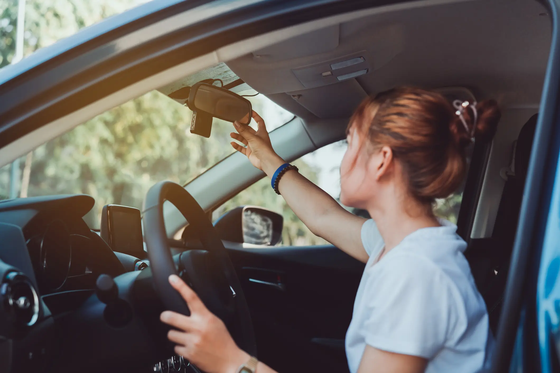 Teen driver checking her rear-view mirror before driving off
