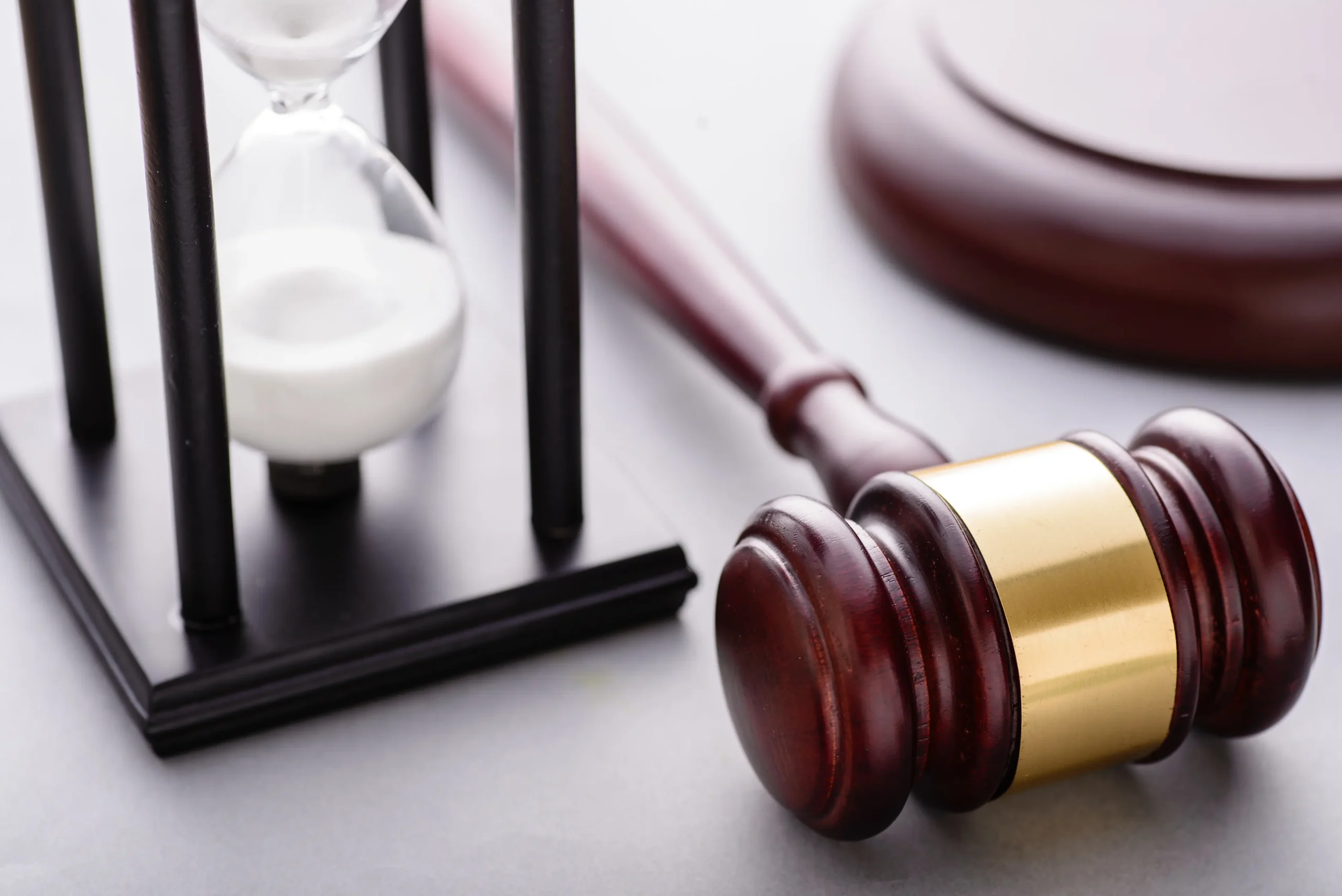 A gavel laying on a judge's desk with an hour glass next to it